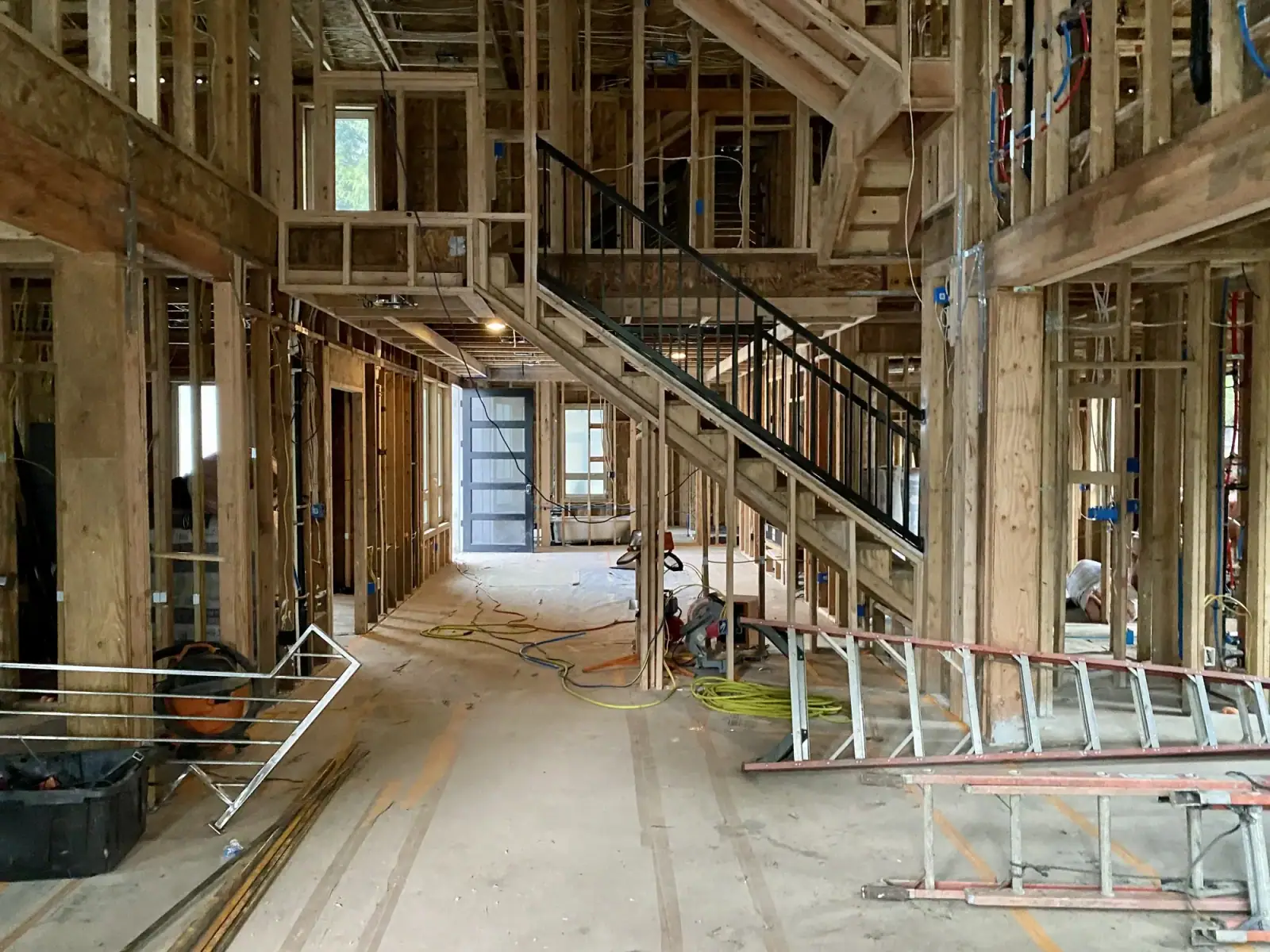 Framed main floor looking toward the stair and arched opening, ladders in place