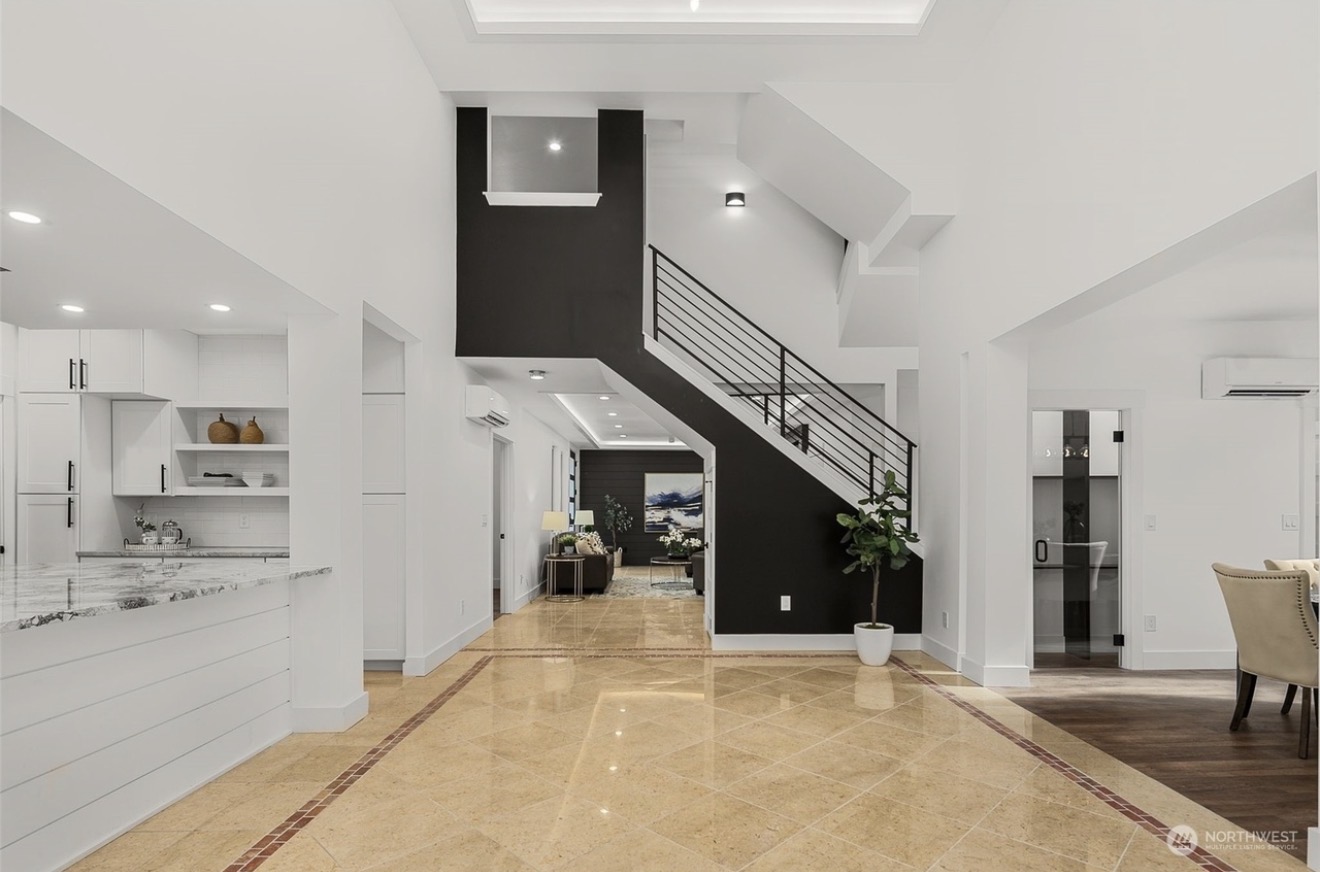 Foyer and stair with black steel railing and polished tile floors, looking toward the kitchen