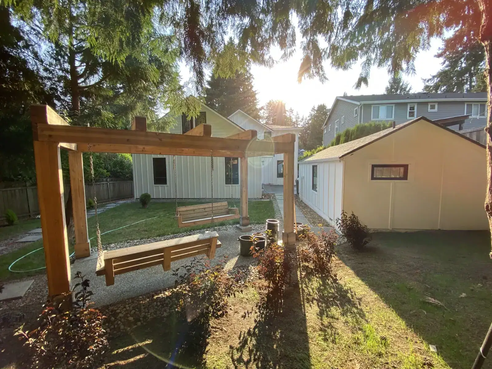 Backyard with a cedar pergola frame under construction beside the shed and lawn
