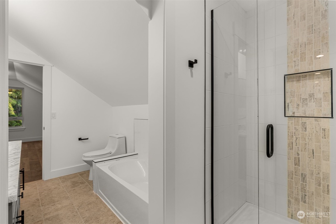 Bathroom with a soaking tub, tiled shower, and glass door