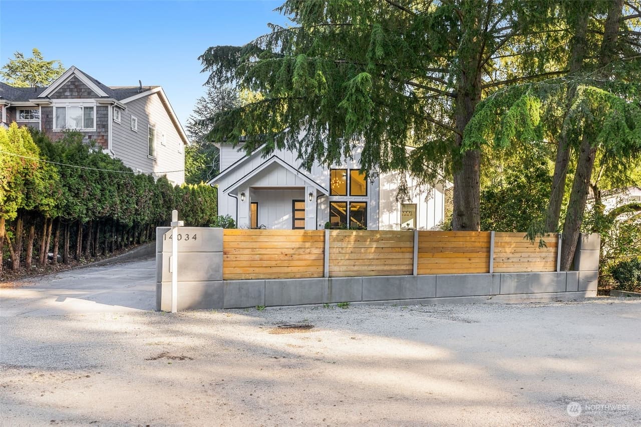 Street view of the new home behind a horizontal cedar-slat fence and concrete driveway