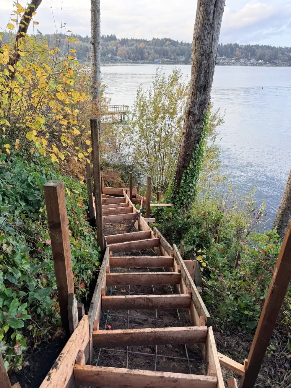Long run of stepped forms with rebar mesh descending the slope to the beach