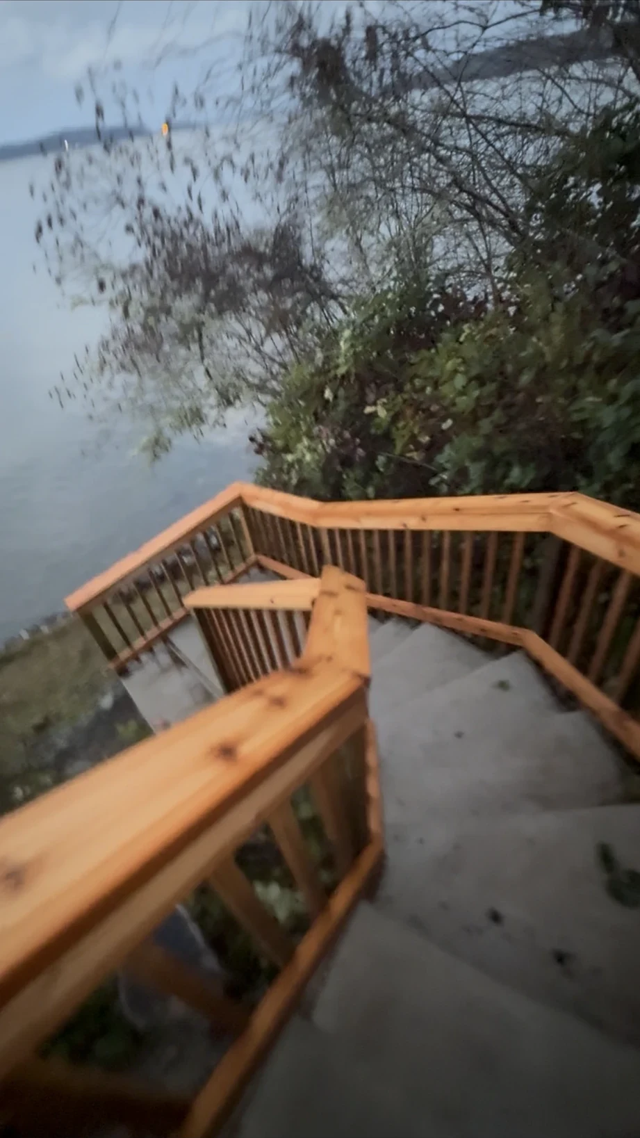 Cedar railing wrapping a landing where the stair turns, with the Sound beyond