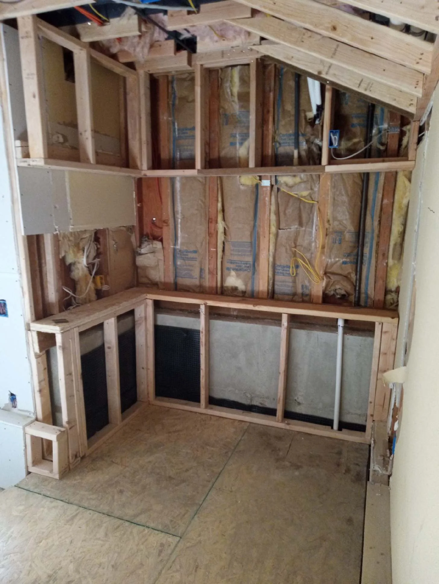 Newly framed walls with insulation and a soffit framed for equipment