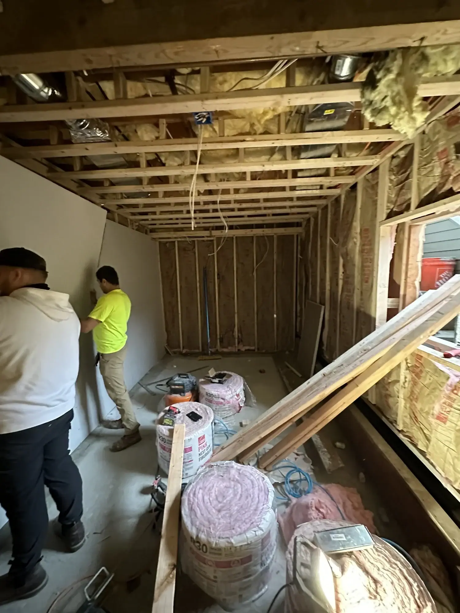 Crew installing insulation batts into the new theater walls