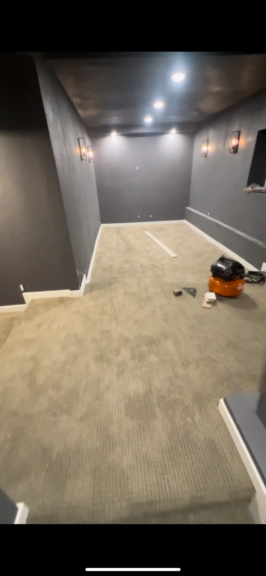 Dark gray theater walls with carpet installed and a wall sconce