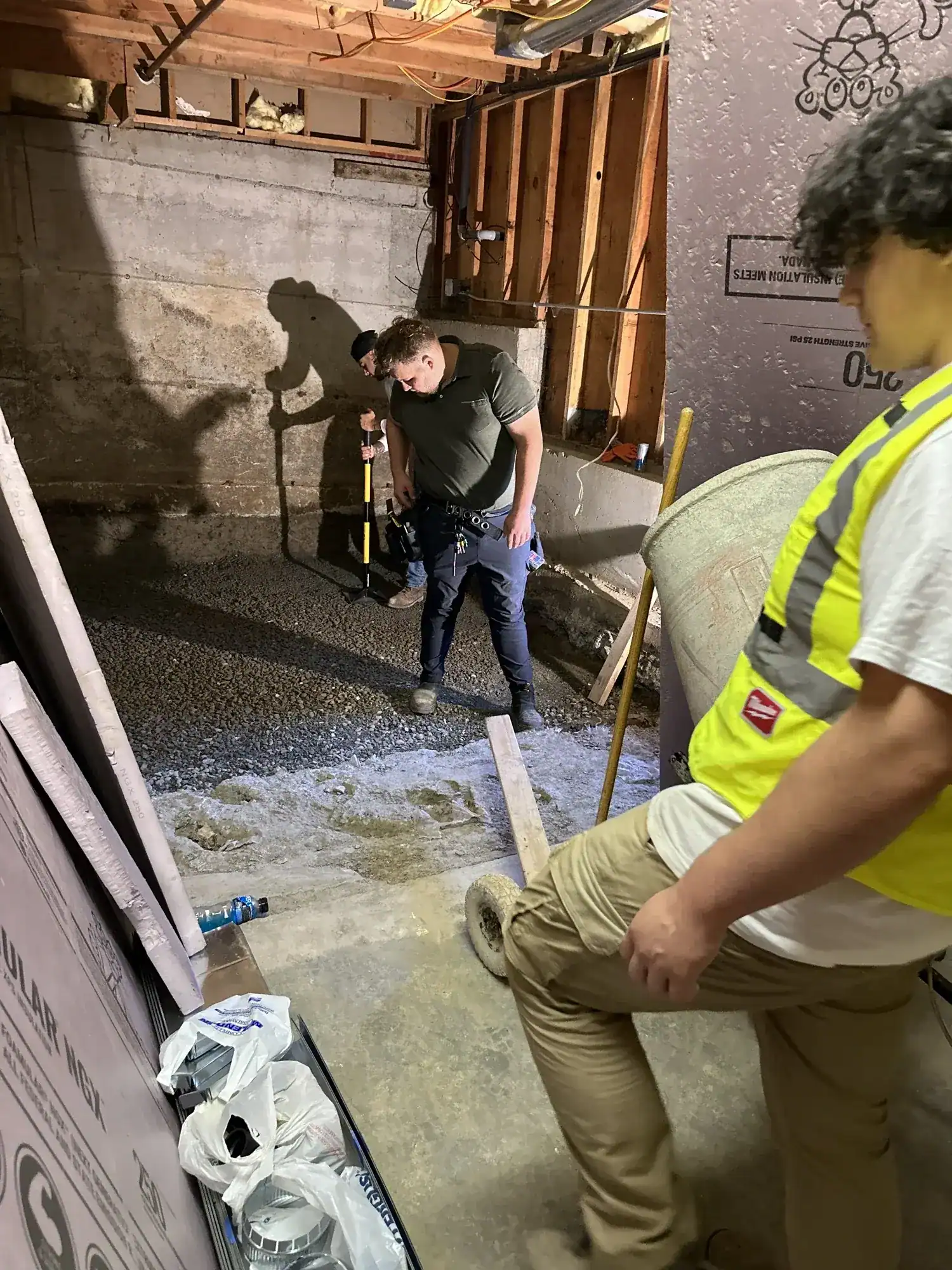 Crew in safety vests placing concrete for the new basement slab