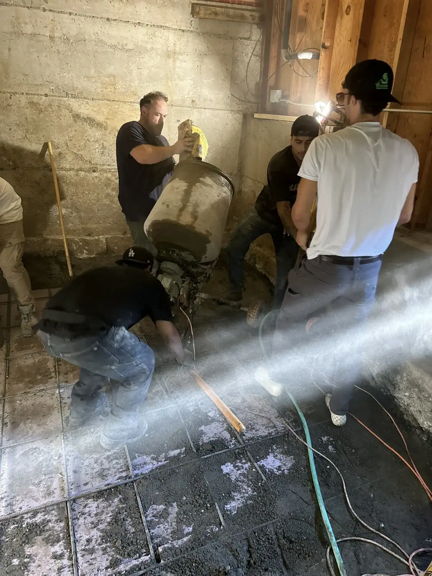 Crew screeding fresh concrete across the underpinned basement floor