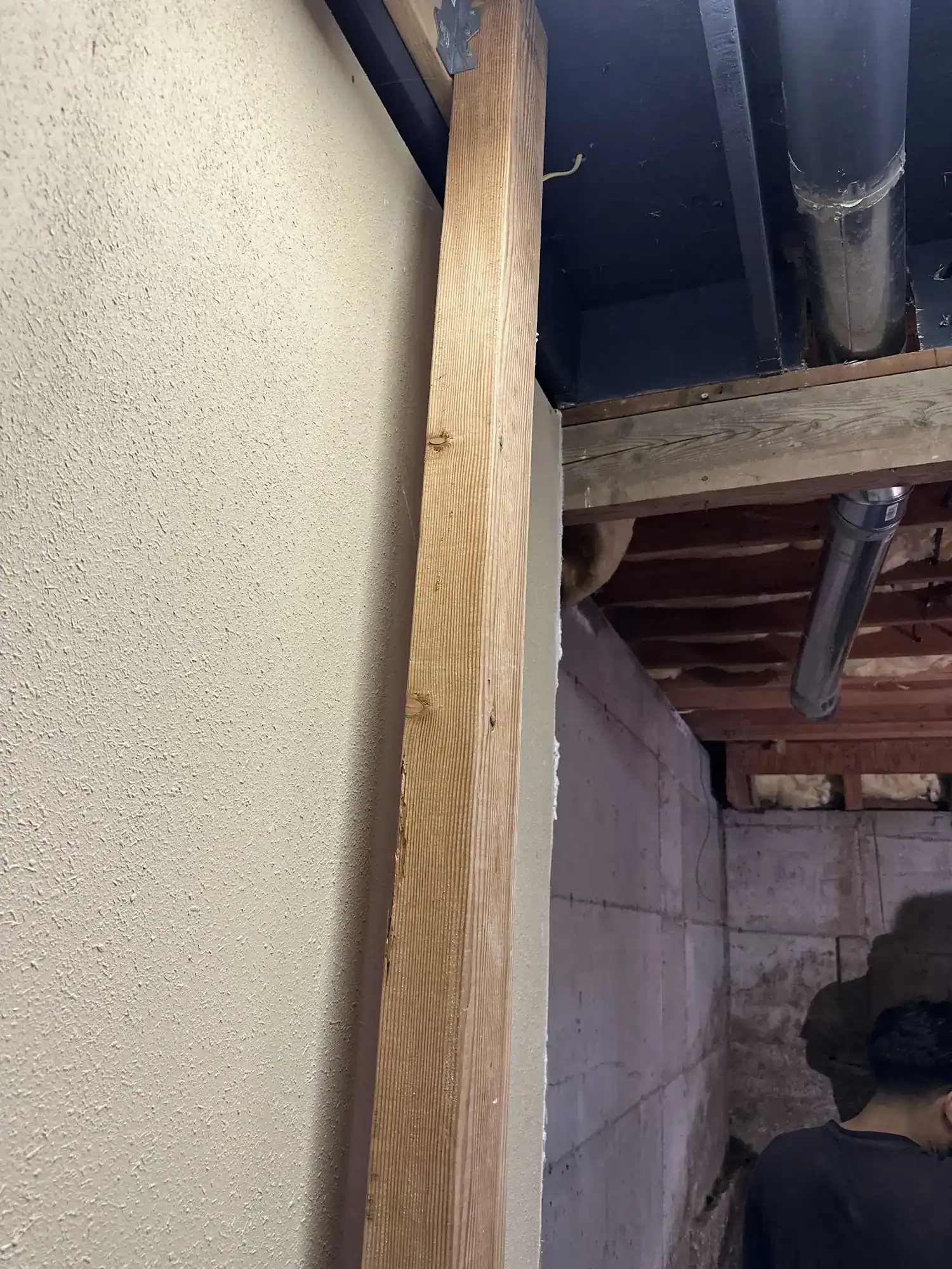 New framing lumber staged against the foundation wall beneath the ceiling joists