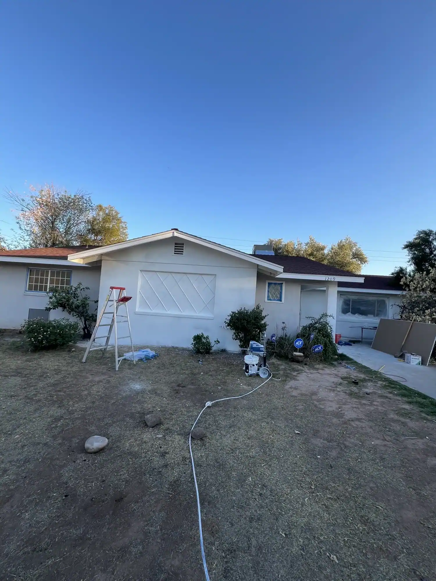 Before: bare dirt front yard and the unpainted house at dusk