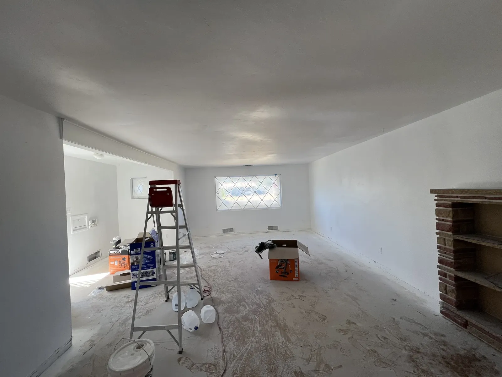Interior during drywall and skim coat with a ladder on the bare concrete floor
