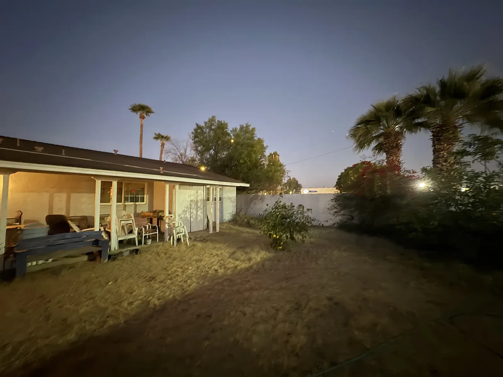 Before: patchy backyard lawn and covered patio at dusk