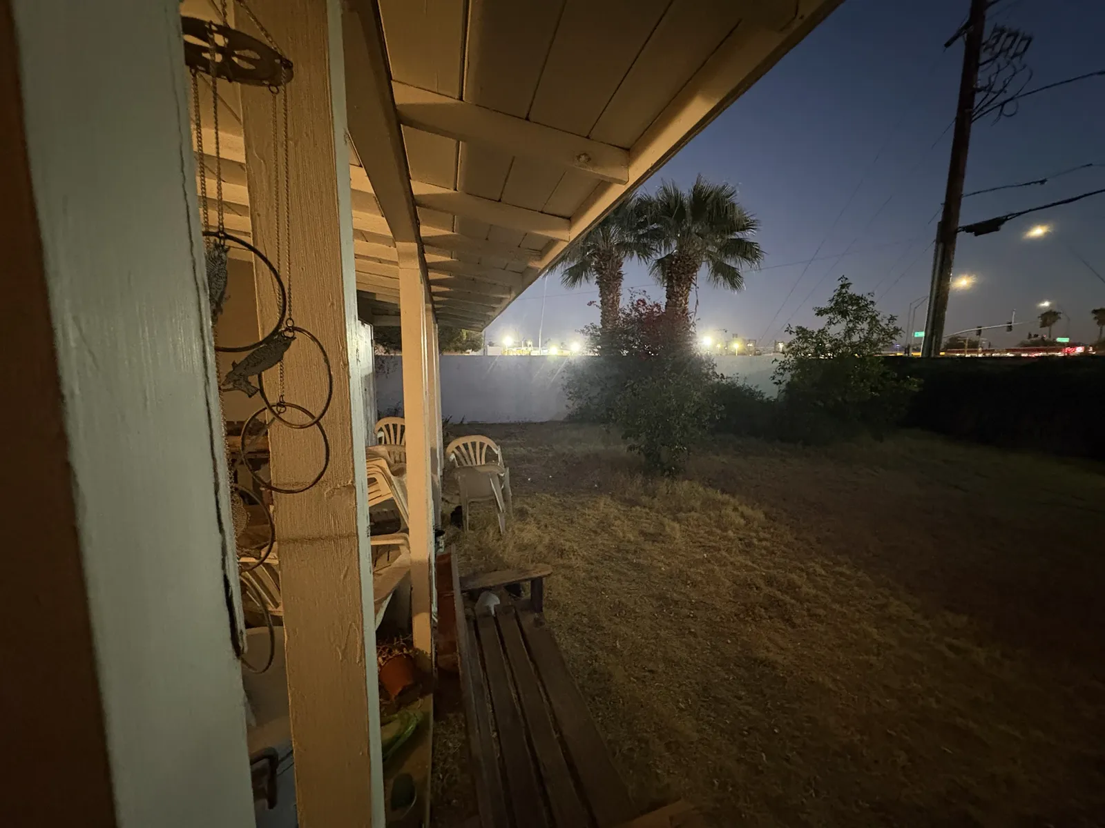 Before: covered patio cluttered with furniture and junk at dusk