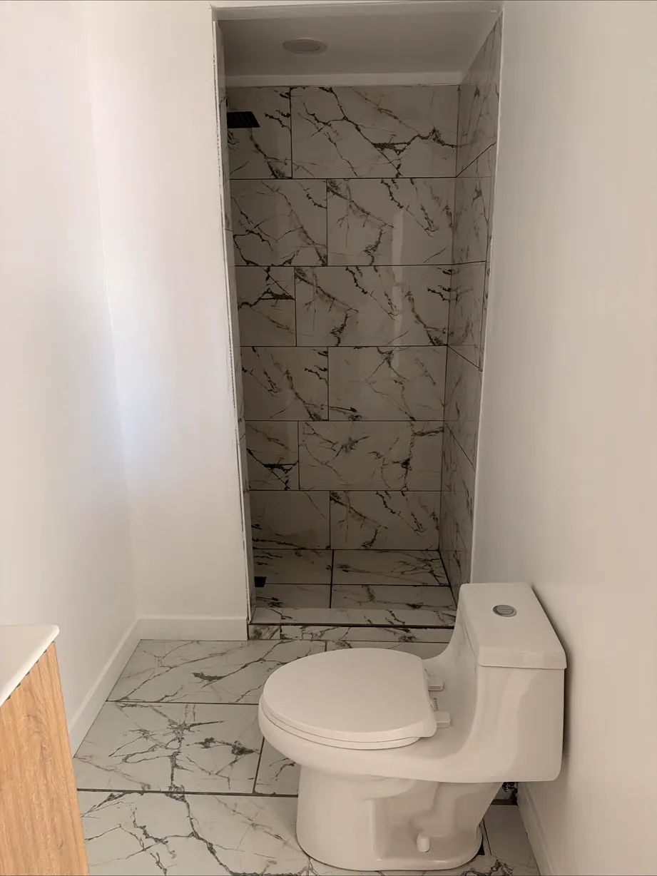 Bathroom with marble-look floor tile set and the toilet installed during tiling