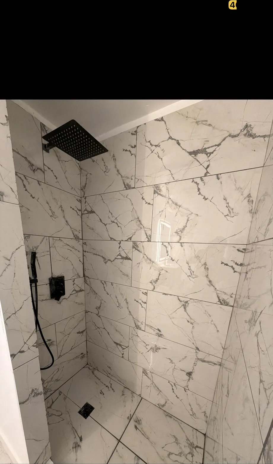 Marble-look tile shower with a matte-black rain shower head