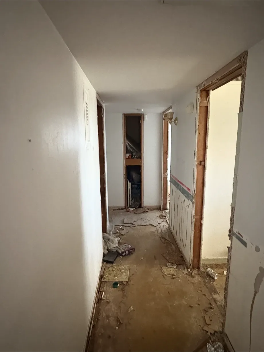 Hallway gutted to bare walls during demolition