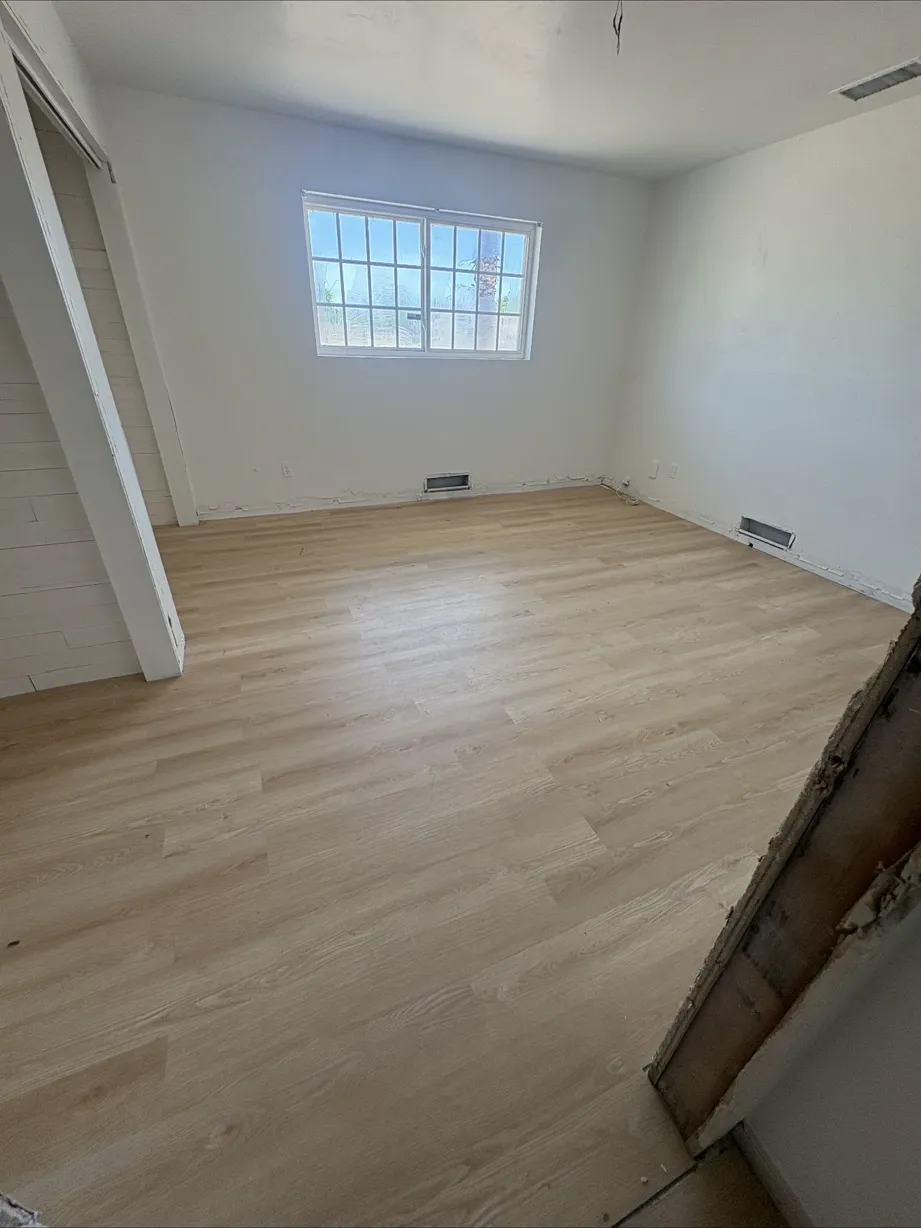 Bedroom with new wide-plank LVP flooring and primed walls